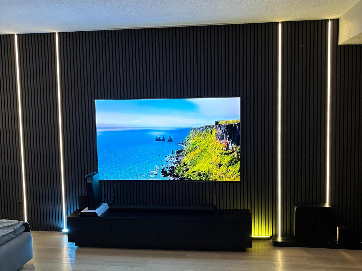 Black slat TV wall with four white LED strips set inside the felt gaps, two on each side of the TV